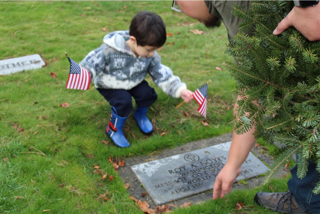 Comrade Guncay and his son lay a wreath on a gravestone.